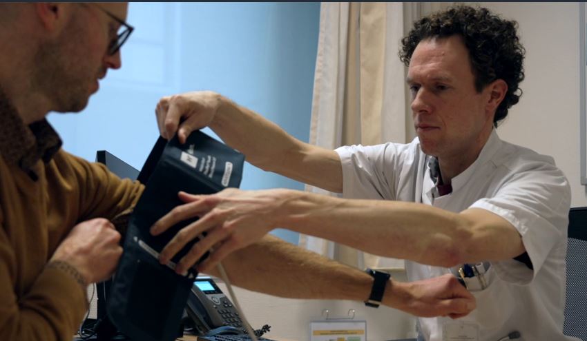 Rutger Brouwers meet de bloeddruk van een patiënt.