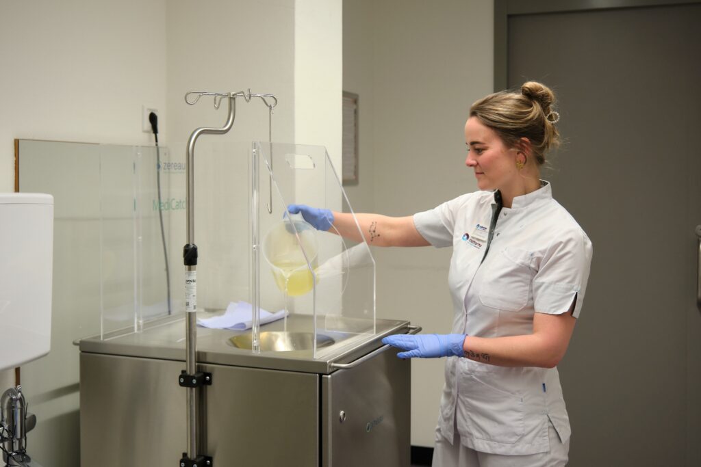 Kim Dirckx leegt een urinezak in het filtersysteem. Foto: Jarno Verhoef/Catharina Ziekenhuis